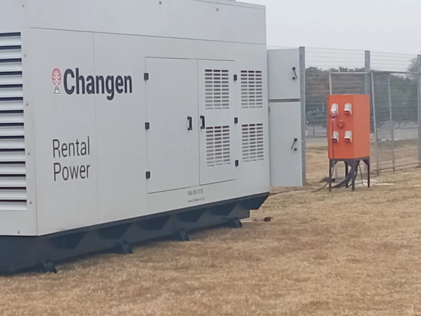 Generator beside a temporary fence and power distribution cabinet