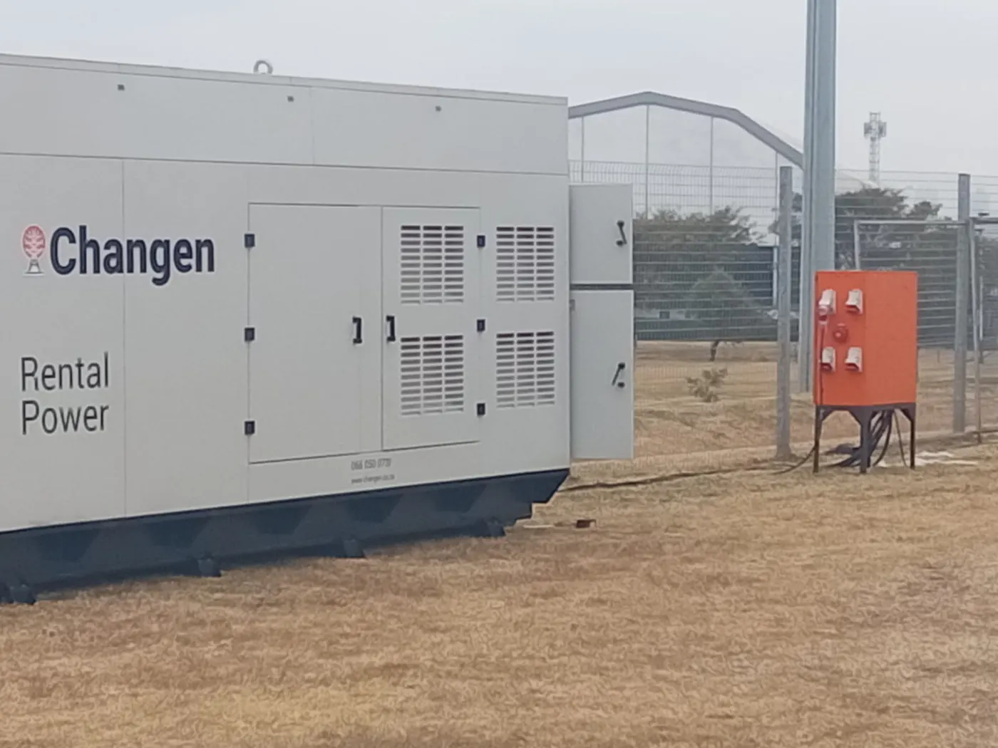 Generator and orange distribution cabinet beside a temporary fence